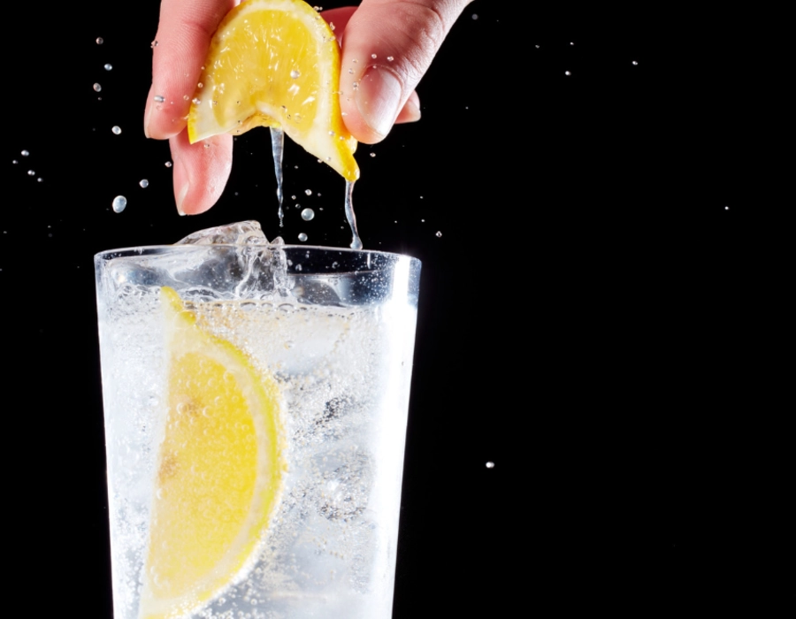 person squeezing lemon into vodka soda