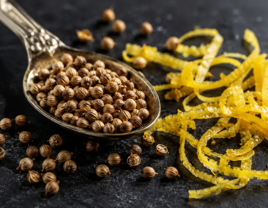 Coriander seeds in a spoon next to lemon zest