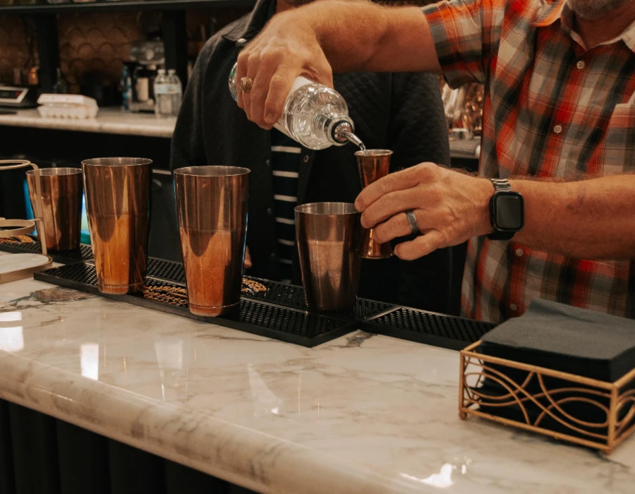 barman pouring hush and whisper vodka into thimble
