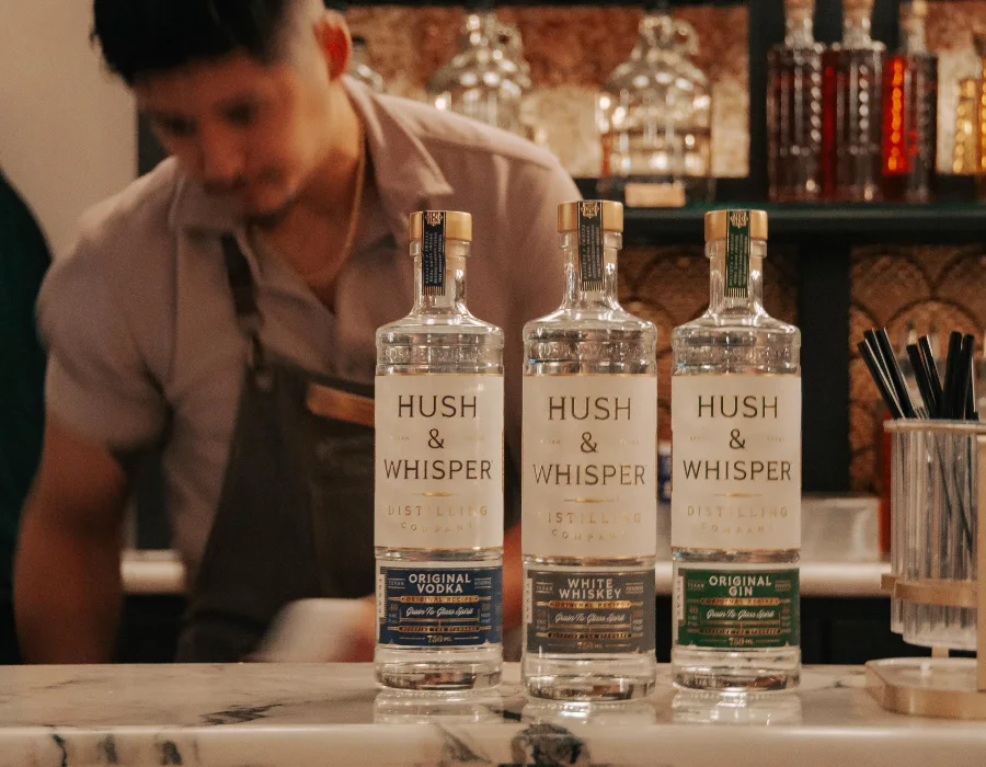 hush and whisper collection on bar with barmen in background