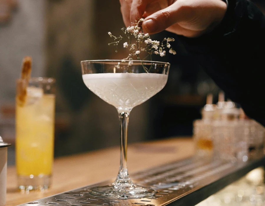 woman taking floral garnish off martini
