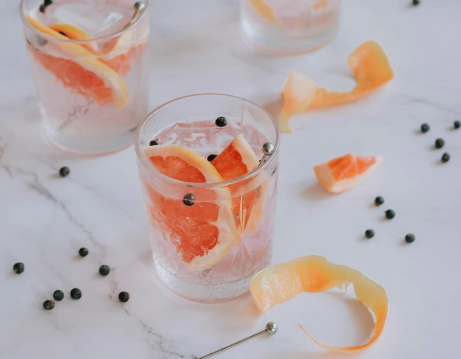 shot glasses with grapefruit, pepper corns and gin on marble slab