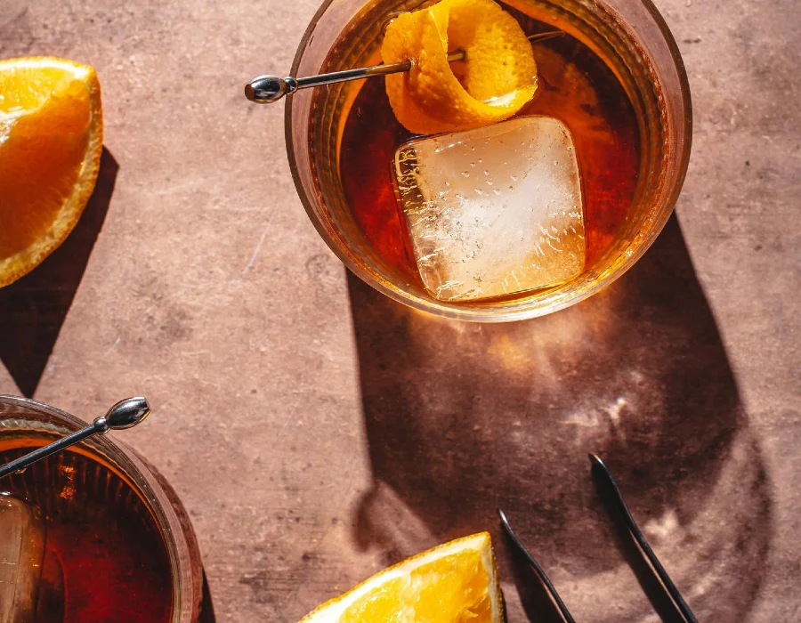 slice of orange on table with two liquor cocktails