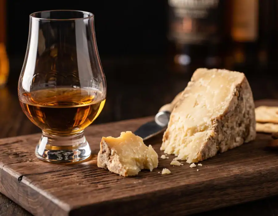 glass of whiskey and cheese on a wooden plank