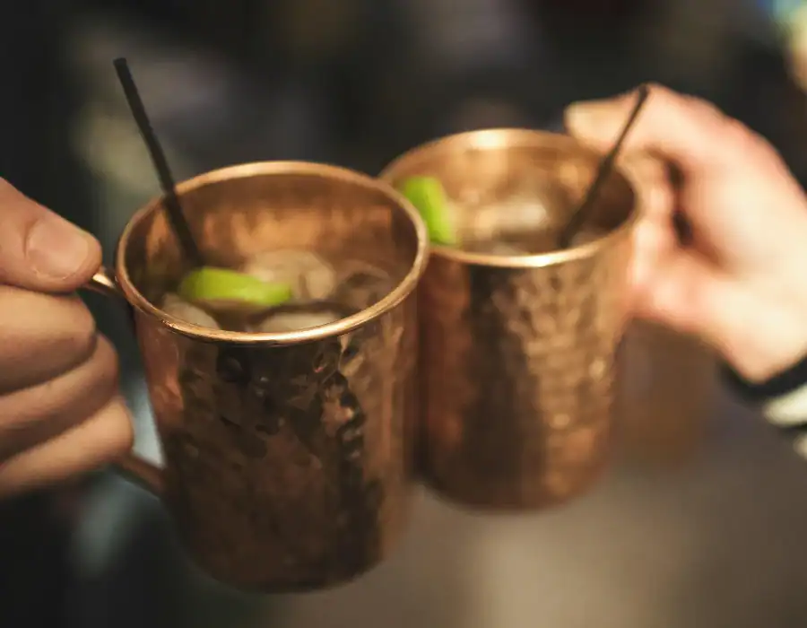 people giving a cheers with copper mugs