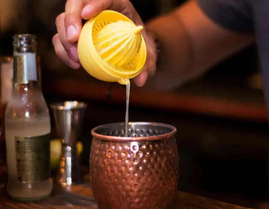 person pouring lemon juice into copper mug